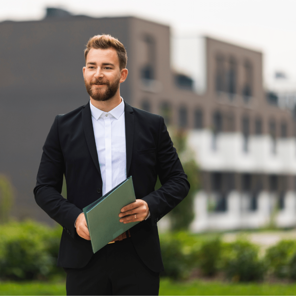 Man in formal attire standing holding a file
